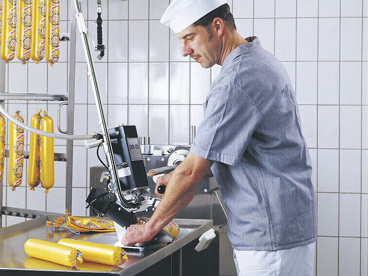 Butcher working with manual clipping machine